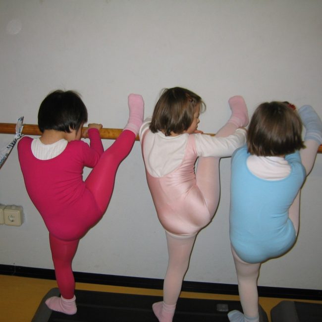 Grupo de tres niñas en mallas estirando
